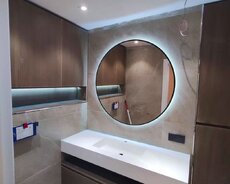 Dairəvi işıqlı güzgü və ağ rəngli, iki hissəli dolablı lavabo. Müasir